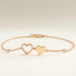 Gold bracelet with heart charms on a wrist against a neutral background