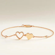 Gold bracelet with heart charms on a wrist against a neutral background