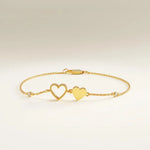 Gold bracelet with heart charms on a wrist against a neutral background