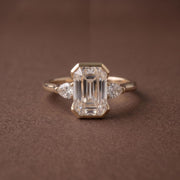 3 stone emerald engagement ring with elegant diamond setting